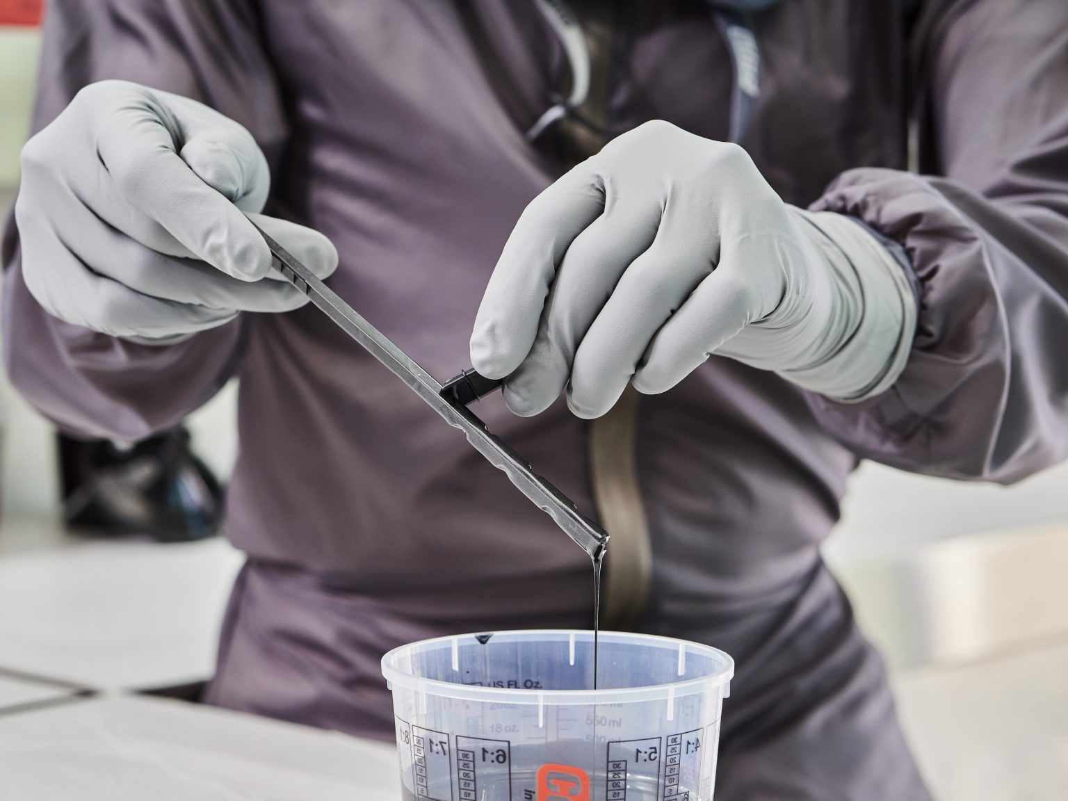 Profissional fazendo uso da luva de nitrillo cinza para manusear tinta